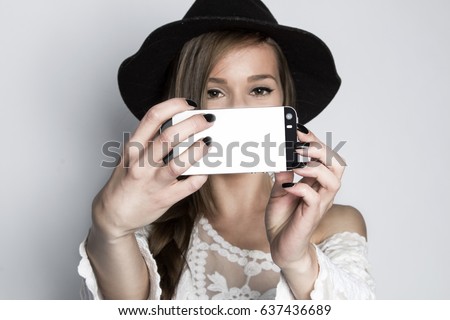 Girl taking selfie with phone, studio shot