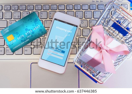 On-line shopping concept - shop cart with giftbox, credit card and phone