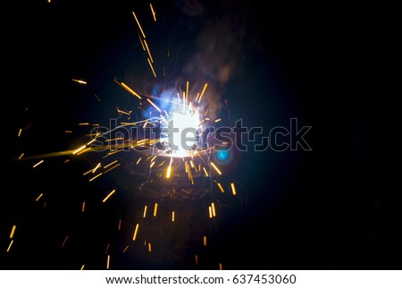 Bright blue and yellow sparks on a black background. Magical lights in the night. Flashes of light and sparks from welding.