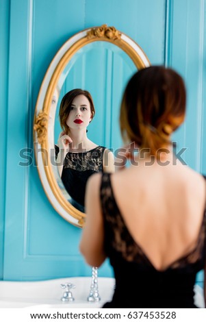 portrait of beautiful young woman looking at herself in the wonderful mirror