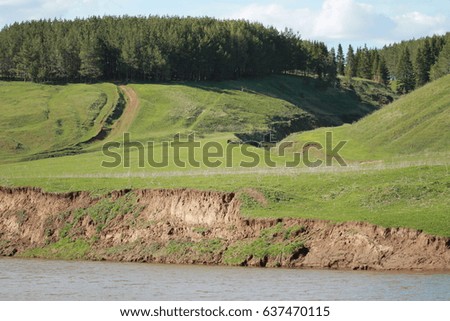 A wonderful landscape with rolling hills and a pronounced coastline with high banks. Spring juicy grass atmospheric fresh air, blue sky. The river flows on the surface of the water wave