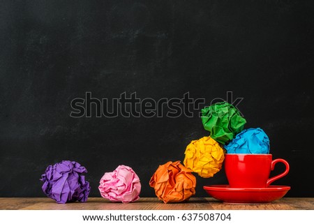 colorful rainbow paper balls on wood texture floor table with red coffee cups stack together on blackboard wall background display advertising area.
