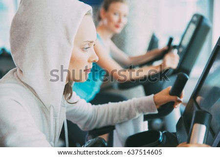 Two serious women cycling on exercise bikes in gym