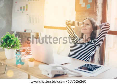 Portrait of happy beautiful smiling woman sitting at the table and dreaming about weekend. Intentional sun glare, lens flares effect