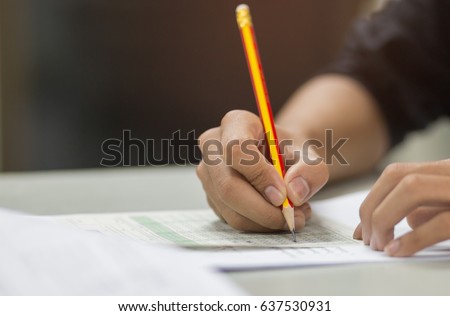 students hand testing doing examination with pencil drawing selected choice on answer sheets in school exam at  college