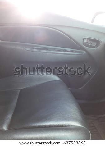 Close-up picture of black leather seats inside the car, back in the morning light into the car door.