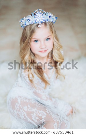 Little happy blonde girl in white dress and crown