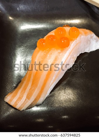 Salmon Ikura sushi made from fresh salmon and salmon roe on top in black dish. 