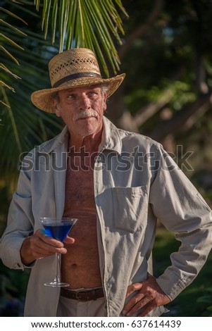 Male baby boomer in straw hat enjoying a cocktail in a tropical location
