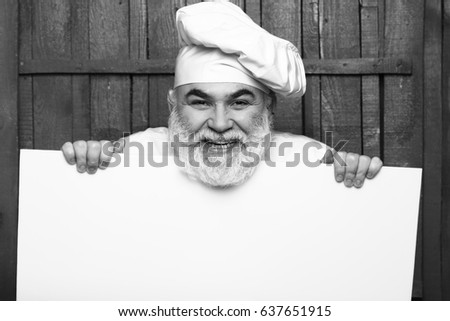 Emotional cook holding blank paper on wooden background, copy space