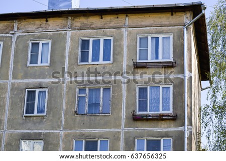 The facade of the old multi-storey residential building of the times of Khrushchev (USSR). Gray faceless windows and walls. Russia. Royalty-Free Stock Photo #637656325