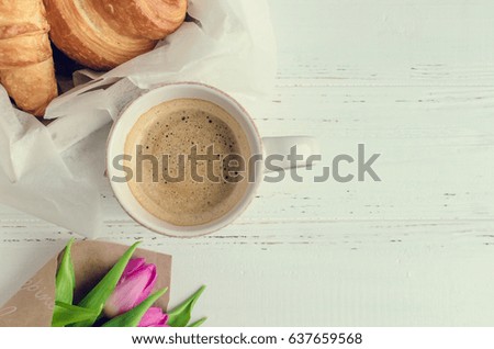 Cup of coffee with bouquet of pink tulips and croissant on white shabby chic background. Valentines, Mothers, Womens Day morning concept. Valentine's day breakfast. Top view. Copy space.