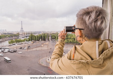 The girl is taking pictures of the Paris view on the smartphone. View from the Ferris wheel at the Eiffel Tower. The Garden Of Tuileries. soft focus