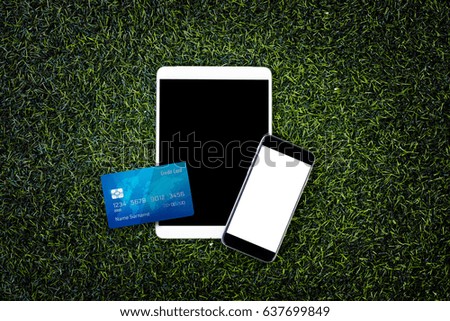 Digital tablet, credit card and mobile phone on the green grass texture background, tablet on the grass, technology concept. business concept. black smart phone concept on dark background.