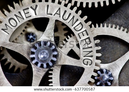 Macro photo of tooth wheel mechanism with MONEY LAUNDERING letters imprinted on metal surface