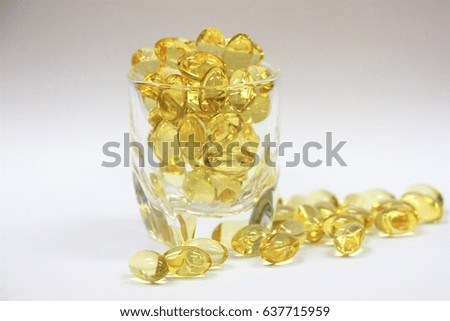A glass of vitamin E capsules on white background.