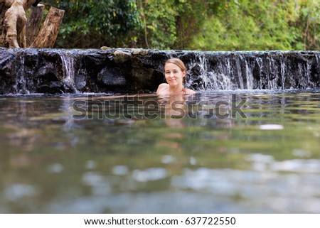 Young caucasian beautiful woman tourist enjoying a bath in Pai Sai Ngam secret hotsprings hidden in jungle in north Thailand. Landscape with men and nature in south east asia during summer.