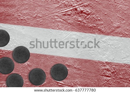 Hockey pucks, and the image of the Latvian flag on the ice. Concept, hockey