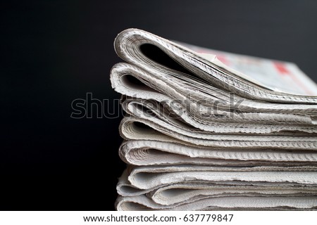 Stack of folded newspapers in front of a black background with copy space Royalty-Free Stock Photo #637779847