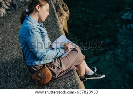 Young Woman writing a diary by the sea