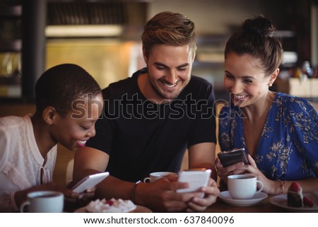 Happy friends using mobile phone while having breakfast in restaurant Royalty-Free Stock Photo #637840096