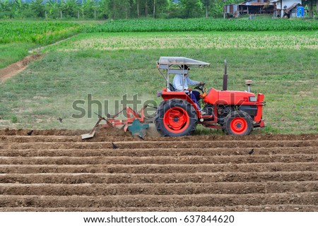 
Red tractor plowing groove in field Thailand..


