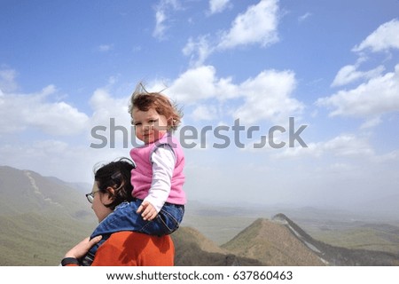 Little baby Mary sitting on shoulders of mother above the sky