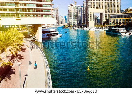 Rays of yellow color cover picture of blue water between skyscrapers in Dubai