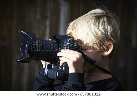 School-age boy with a camera photographing outdoors with dslr camera