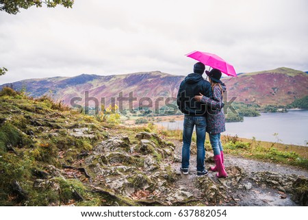 Back view of young couple who stands at the top and looks at wonderful view