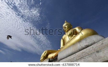 A bird is flying to Buddha statue with blue sky cloud in background