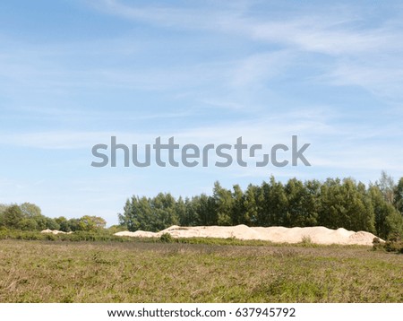 a landscape scene of beauty in the summer with clear field and sky and a sand pile in the far distance spring sunny day