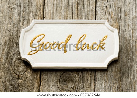 A porcelain tile with "Good luck" sign on the wooden background