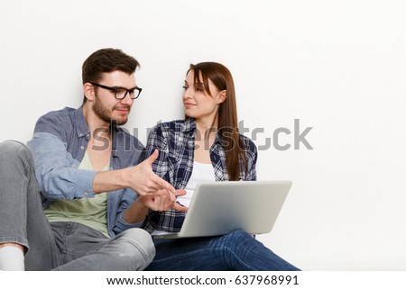 Couple conversation with laptop. Man showing project to woman on computer, pointing on screen, white background, studio shot