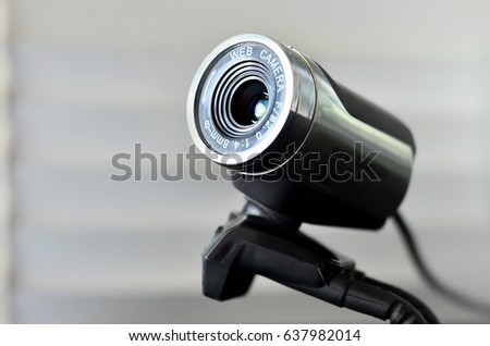 Macro photography of a wired web camera for stationary computers and laptops. A web camera image of a cylindrical shape lying on the computer surface. Focus on the camera 
lens