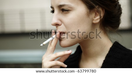 real young woman smokes on the street, selective focus Royalty-Free Stock Photo #63799780