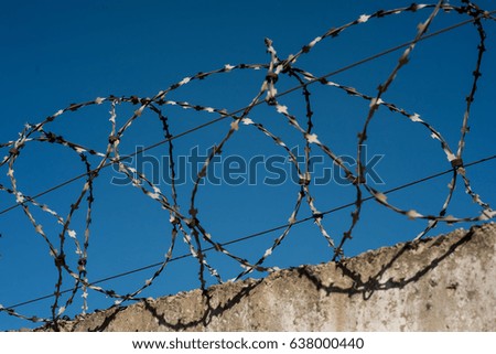 Concrete fence with a barbed wire against the sky