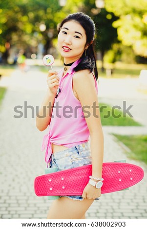 Lovely girl with a penny board in the city park