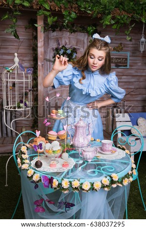Alice at tea-table taking a sweet