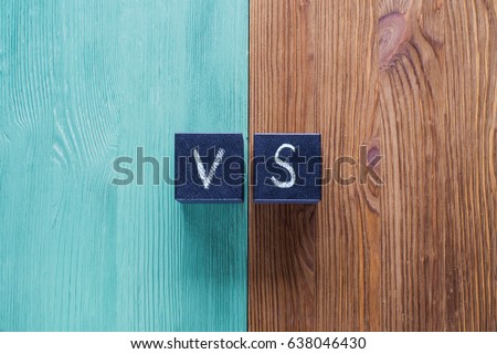 Letters VS on wooden background with copy space. The concept of making choice.  Versus letters. Turquoise and brown wooden background and black cubes with letters VS. Royalty-Free Stock Photo #638046430