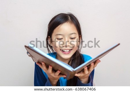Smile happy children girl while reading a book.