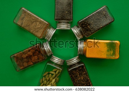 Indian spice boxes arranged in circle in green background 