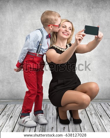 Young mother and son are photographed on a mobile phone ,making selfie .Stylish,trendy,modern