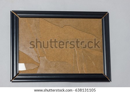black picture frame with broken glass plate in front of grey background