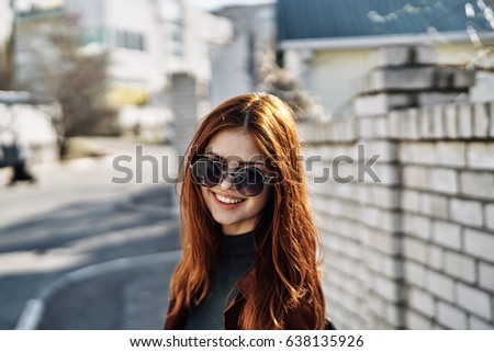 Woman smiling at the background of a brick fence                               