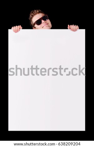 Happy young smiling man on black background showing banner ready for your text or product. Man in sunglasses holding white poster to write it on your own text.