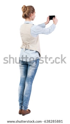 back view of standing young beautiful  woman  in vest and using a mobile phone. girl  watching. Isolated over white background. Girl doing selfie on your phone.