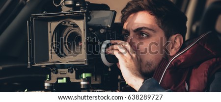 Behind the scene. Cameraman shooting the film scene with his camera on outdoor location Royalty-Free Stock Photo #638289727