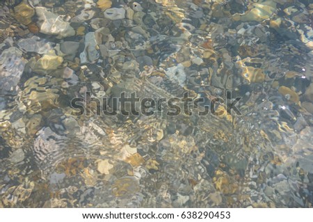sea pebble beach with multicoloured stones, transparent waves with foam, on a warm summer day