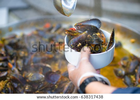 The chef puts mussels, seafood salad. Lovely lunch or dinner. Live healthy food. Close-up of a diver in his hand and a plate of mussels.